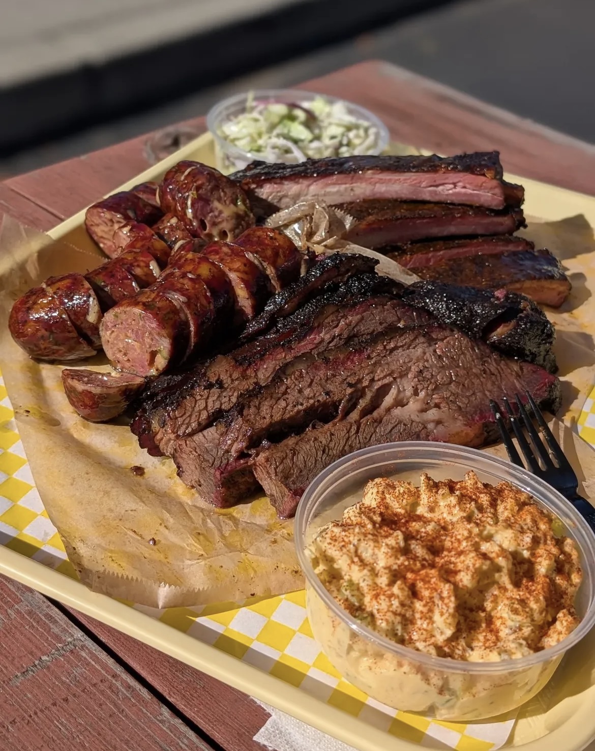 BBQ platter with sliced brisket, sausage, and sides