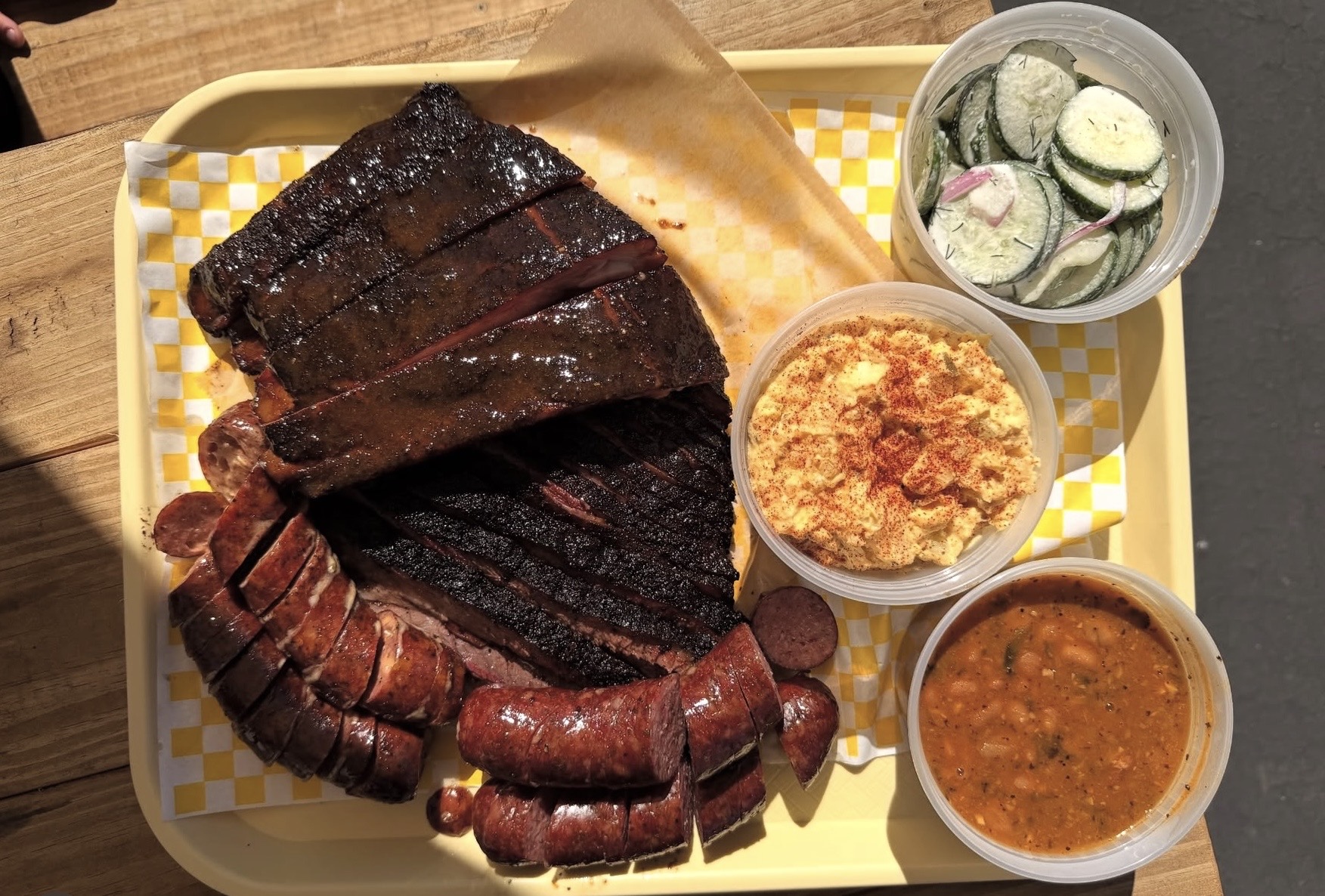 BBQ platter with massive beef ribs, sliced sausage, and all three sides